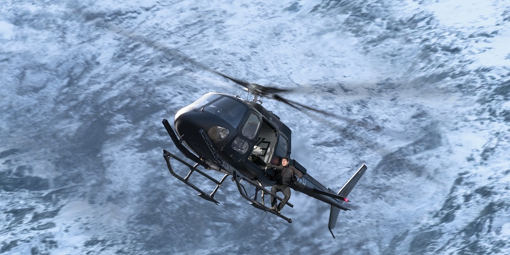 Tom Cruise stands on the outside of a moving helicopter in Mission: Impossible - Fallout