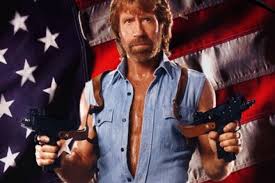 Chuck Norris with guns in both hands in front of an American flag