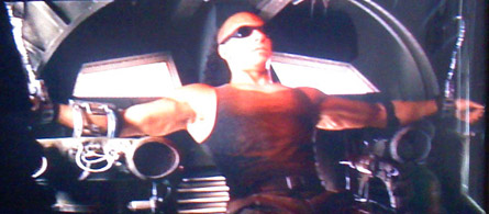 The Chronicles of Riddick, Riddick cuffed about Merc ship