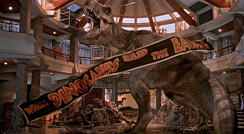 Jurassic Park scene where the t-rex roars in the lobby as the banner reading When Dinosaurs Ruled The Earth falls to his feet